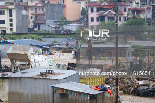 People wait on the top of a truck after being surrounded by a flooded river in Lalitpur, Nepal, on September 28, 2024. At least 32 people di...