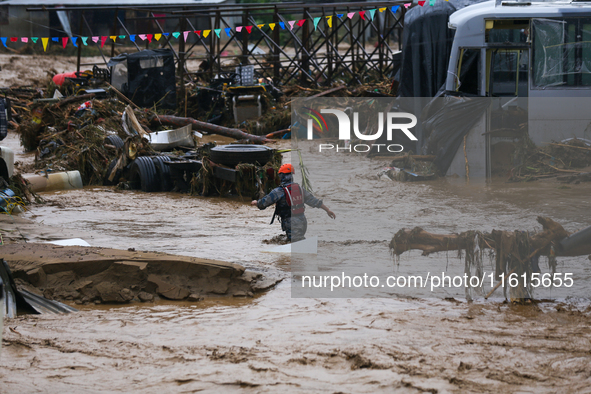 Nepal's Armed Police Force personnel wade through a flooded river to rescue stranded people in Lalitpur, Nepal, on September 28, 2024. At le...