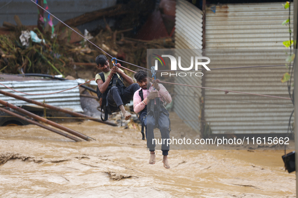 Nepal's Armed Police Force rescues a stranded person using a zipline rescue method from a flooded river in Lalitpur, Nepal, on September 28,...