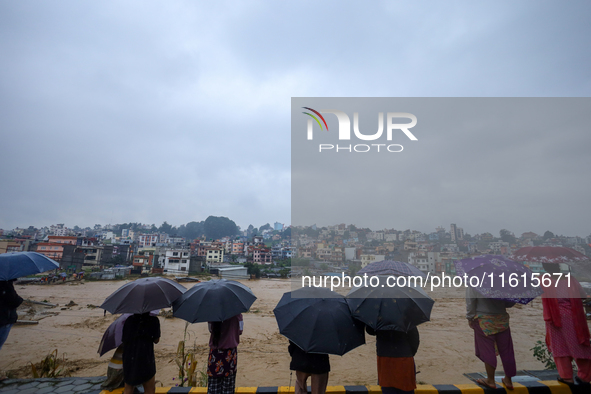 People watch the swollen and flooded Nakkhu River in City, Country, on September 28, 2024. At least 32 people die in the last 24 hours due t...