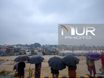 People watch the swollen and flooded Nakkhu River in City, Country, on September 28, 2024. At least 32 people die in the last 24 hours due t...