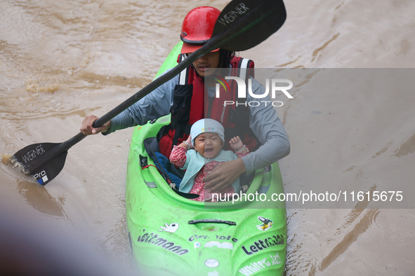 A Nepal Army personnel evacuates an infant using a kayak from a flooded residential area in Kathmandu, Nepal, on September 28, 2024. At leas...