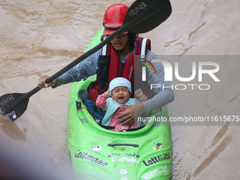 A Nepal Army personnel evacuates an infant using a kayak from a flooded residential area in Kathmandu, Nepal, on September 28, 2024. At leas...