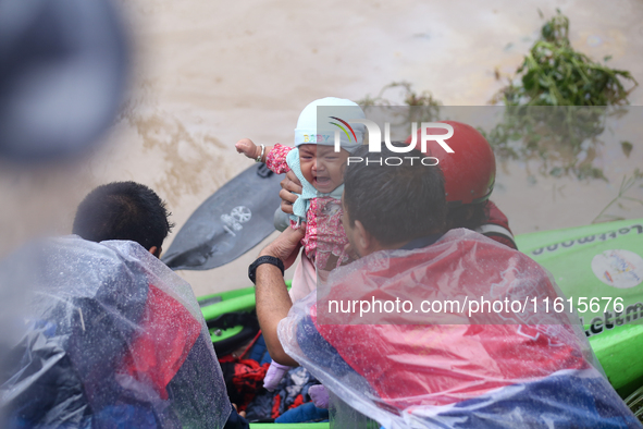 A Nepal Army personnel evacuates an infant using a kayak from a flooded residential area in Kathmandu, Nepal, on September 28, 2024. At leas...