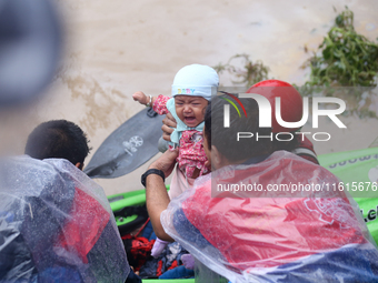 A Nepal Army personnel evacuates an infant using a kayak from a flooded residential area in Kathmandu, Nepal, on September 28, 2024. At leas...