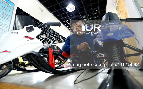 A staff member repairs a children's snowmobile at the Qilian Mountain ski resort in Zhangye, China, on September 28, 2024. 