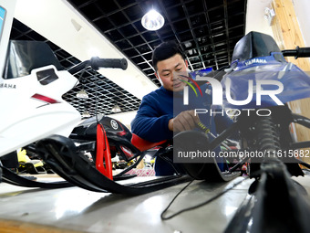 A staff member repairs a children's snowmobile at the Qilian Mountain ski resort in Zhangye, China, on September 28, 2024. (