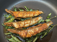 Sardines coated with masala spices fry in a pan as Kerala style mathi fry (sardine fish fry) is prepared in Toronto, Ontario, Canada, on Sep...