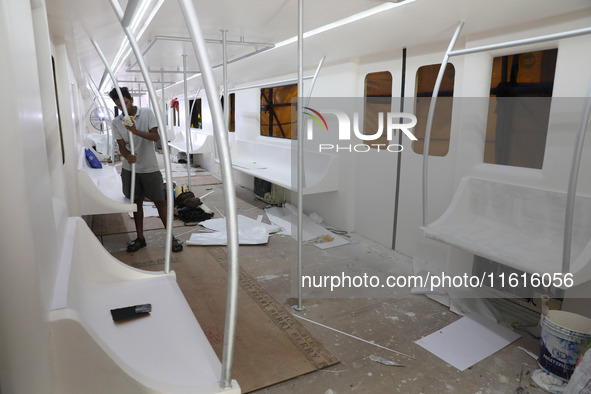 An artisan works inside a model of a metro compartment in a ''pandal'' or temporary platform ahead of the Durga Puja festival in India on Se...