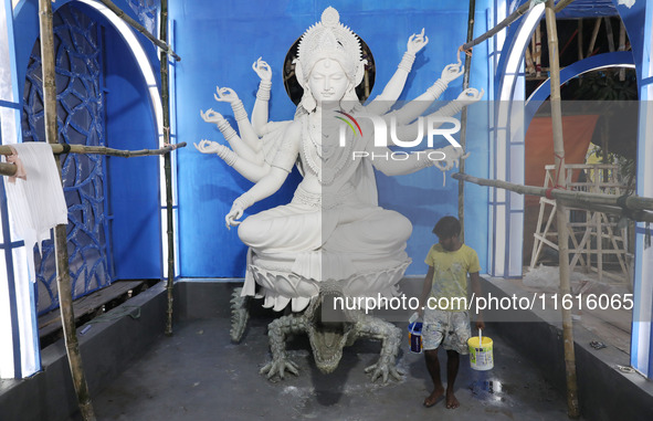 An artisan paints near idols of the Hindu goddess Durga under the Hooghly River, visible from a model of a metro compartment ahead of the Du...