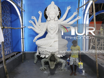 An artisan paints near idols of the Hindu goddess Durga under the Hooghly River, visible from a model of a metro compartment ahead of the Du...