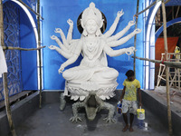 An artisan paints near idols of the Hindu goddess Durga under the Hooghly River, visible from a model of a metro compartment ahead of the Du...