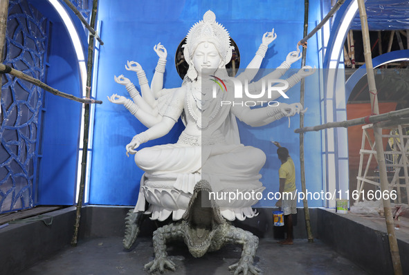 An artisan paints near idols of the Hindu goddess Durga under the Hooghly River, visible from a model of a metro compartment ahead of the Du...