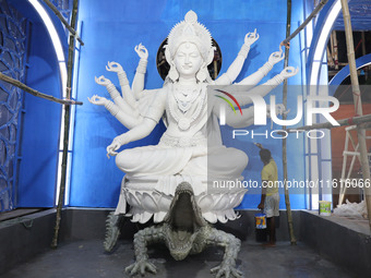 An artisan paints near idols of the Hindu goddess Durga under the Hooghly River, visible from a model of a metro compartment ahead of the Du...