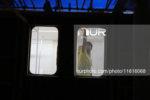 An artisan works inside a model of a metro compartment in a ''pandal'' or temporary platform ahead of the Durga Puja festival in India on Se...