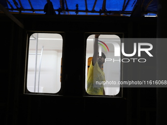 An artisan works inside a model of a metro compartment in a ''pandal'' or temporary platform ahead of the Durga Puja festival in India on Se...