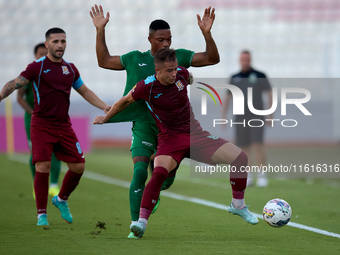 In Ta' Qali, Malta, on September 27, 2024, Thiago Espindola de Paula of Gzira United is challenged from the back by Kemar Reid of Floriana d...