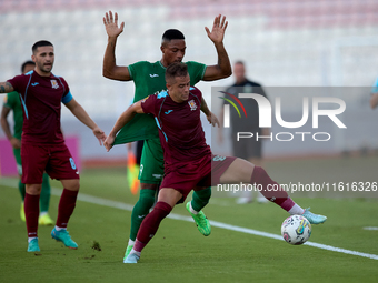 In Ta' Qali, Malta, on September 27, 2024, Thiago Espindola de Paula of Gzira United is challenged from the back by Kemar Reid of Floriana d...