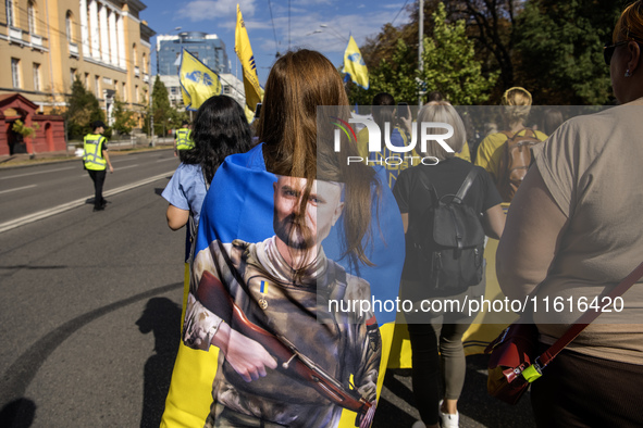 People carry flags with portraits of a fallen Ukrainian soldier during a march marking the upcoming Defenders of Ukraine Day in Kyiv, Ukrain...