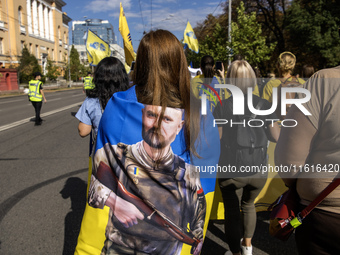 People carry flags with portraits of a fallen Ukrainian soldier during a march marking the upcoming Defenders of Ukraine Day in Kyiv, Ukrain...