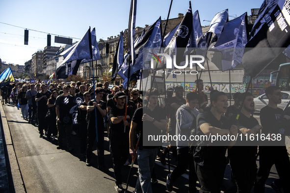 People carry flags with portraits of a fallen Ukrainian soldier during a march marking the upcoming Defenders of Ukraine Day in Kyiv, Ukrain...