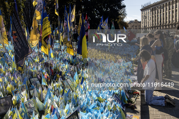 A woman commemorates fallen Ukrainian soldiers at a memorial in Independence Square during a march marking the upcoming Defenders of Ukraine...