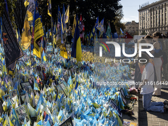 A woman commemorates fallen Ukrainian soldiers at a memorial in Independence Square during a march marking the upcoming Defenders of Ukraine...