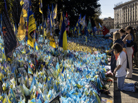 A woman commemorates fallen Ukrainian soldiers at a memorial in Independence Square during a march marking the upcoming Defenders of Ukraine...