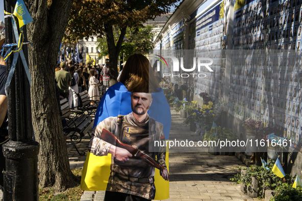 People carry flags with portraits of a fallen Ukrainian soldier during a march marking the upcoming Defenders of Ukraine Day in Kyiv, Ukrain...