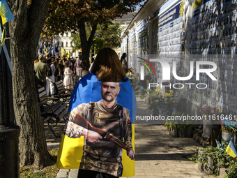 People carry flags with portraits of a fallen Ukrainian soldier during a march marking the upcoming Defenders of Ukraine Day in Kyiv, Ukrain...