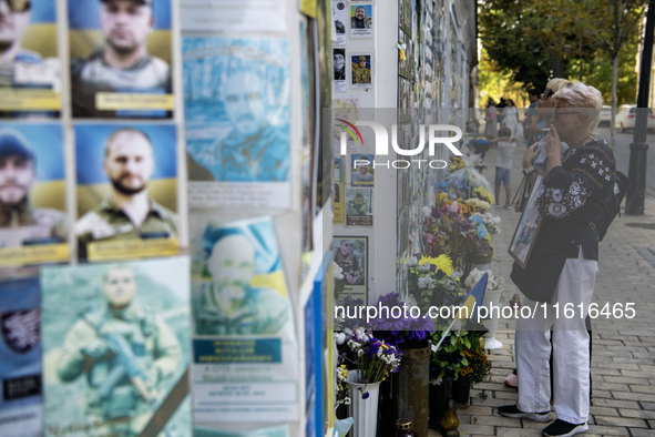 A woman commemorates a fallen Ukrainian soldier at a memorial wall during a march marking the upcoming Defenders of Ukraine Day in Kyiv, Ukr...