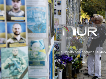 A woman commemorates a fallen Ukrainian soldier at a memorial wall during a march marking the upcoming Defenders of Ukraine Day in Kyiv, Ukr...