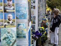 A woman commemorates a fallen Ukrainian soldier at a memorial wall during a march marking the upcoming Defenders of Ukraine Day in Kyiv, Ukr...