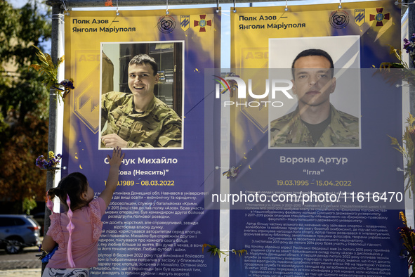 A little girl touches the portrait of her father, who was killed fighting with the Azov brigade in Mariupol, during a march marking the upco...