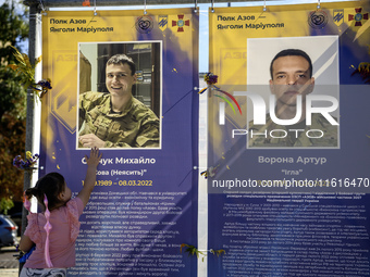 A little girl touches the portrait of her father, who was killed fighting with the Azov brigade in Mariupol, during a march marking the upco...