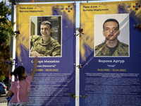 A little girl touches the portrait of her father, who was killed fighting with the Azov brigade in Mariupol, during a march marking the upco...