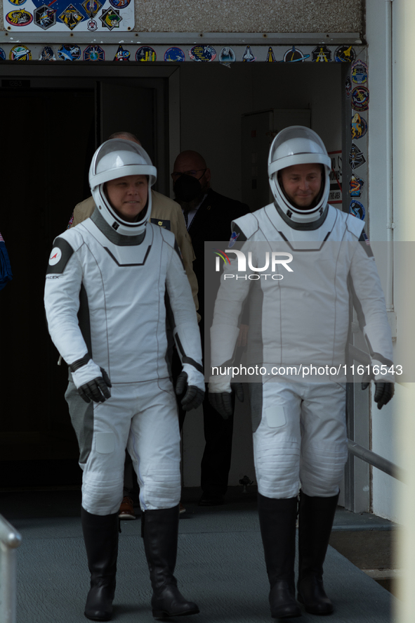 Astronauts Nick Hague and Alexander Gorbunov emerge from the astronaut clean room to begin their journey to the launch pad 