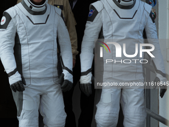 Astronauts Nick Hague and Alexander Gorbunov emerge from the astronaut clean room to begin their journey to the launch pad (