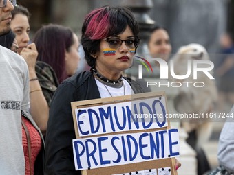 A woman with a Venezuelan flag drawn on her face and carrying a banner with political slogans gathers during a demonstration at Restauradore...