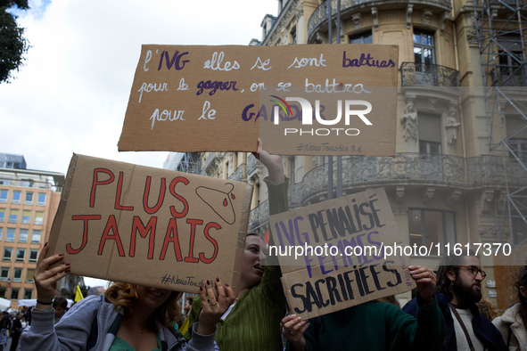 Women hold placards reading (left to right) 'Never again' and 'Right to abortion, they fought to win it, we'll fight for keeping it'. For In...