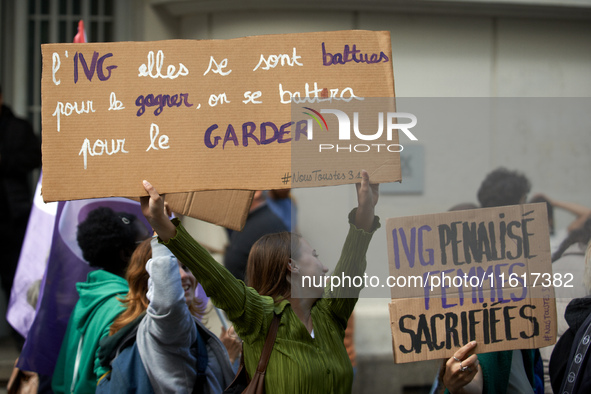 A young woman holds a cardboard sign reading 'Safe Abortion they fought for it, we'll fight to keep it' and 'Abortion forbidden, women sacri...