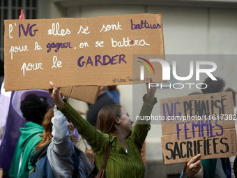 A young woman holds a cardboard sign reading 'Safe Abortion they fought for it, we'll fight to keep it' and 'Abortion forbidden, women sacri...