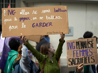 A young woman holds a cardboard sign reading 'Safe Abortion they fought for it, we'll fight to keep it' and 'Abortion forbidden, women sacri...