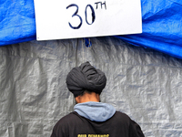 An organizer adjusts a tent and sets up for a protest at an international students' encampment in Brampton, Canada, on September 28, 2024. T...