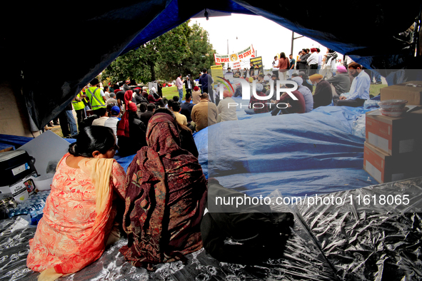 Two women sit in a tent and listen to speakers during a protest rally at an international students' encampment in Brampton, Canada, on Septe...