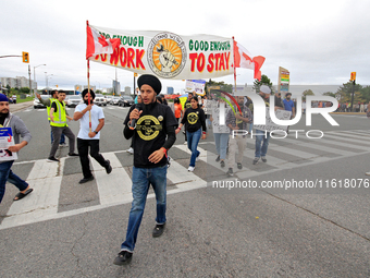 Participants walk across Queen Street during a protest rally at an international students' encampment in Brampton, Canada, on September 28,...