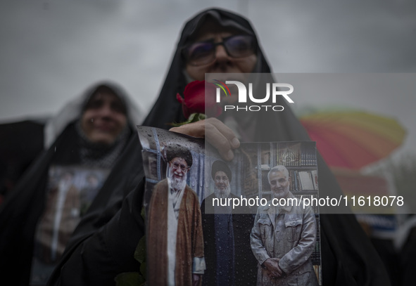 A veiled Iranian protester holds a poster featuring portraits of the former commander of the Islamic Revolutionary Guard Corps' (IRGC) Quds...