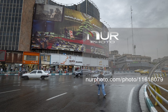 A young Iranian woman walks under an anti-Israeli giant billboard before a protest gathering to condemn an Israeli air strike against Hezbol...