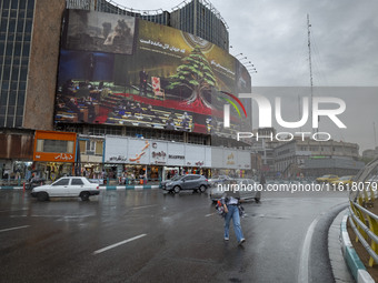 A young Iranian woman walks under an anti-Israeli giant billboard before a protest gathering to condemn an Israeli air strike against Hezbol...