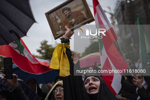 A veiled Iranian protester mourns while holding a framed portrait of Lebanon's Hezbollah Secretary General, Hassan Nasrallah, during a prote...